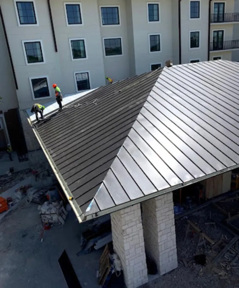 Crew installing standing seam metal roof panels on a commercial project in Punxsutawney